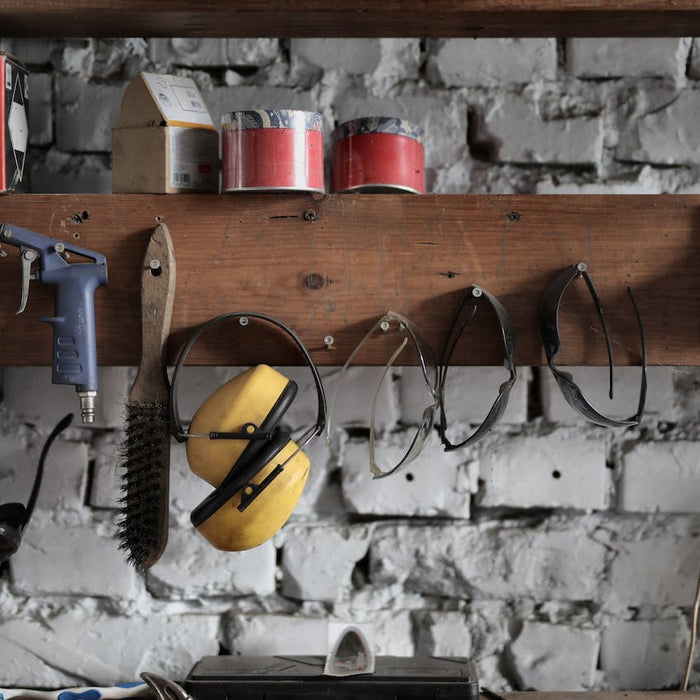 Basic construction tools hanging on a wooden board in a garage.