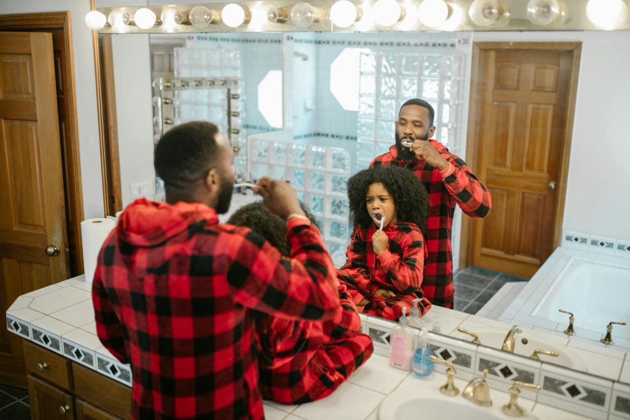 A father and a kid brushing their teeth in the bathroom