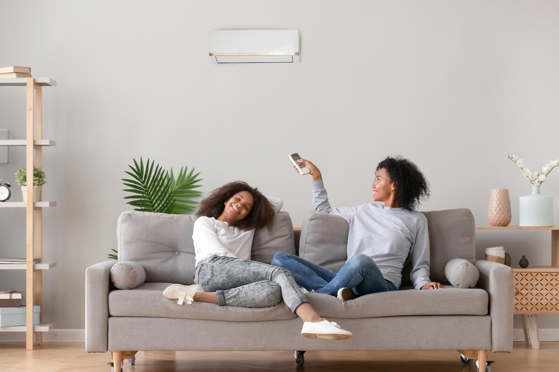 A woman on a couch adjusting air conditioner