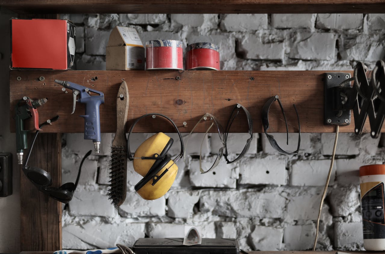 Basic construction tools hanging on a wooden board in a garage.