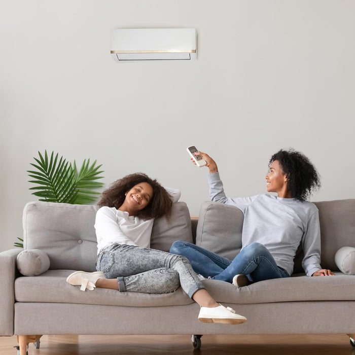 A woman on a couch adjusting air conditioner
